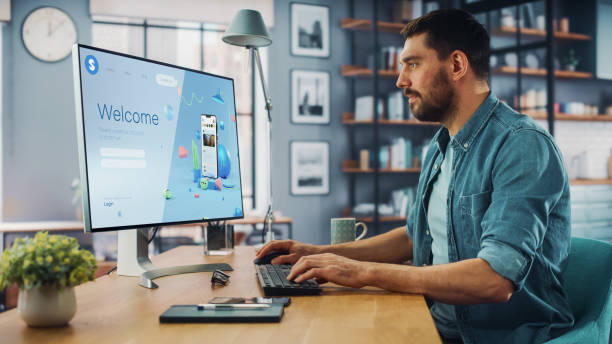 istock Handsome Caucasian Male is Using Desktop Computer that Shows Welcome Page of a Popular Social Network. Freelance Man Working Over the Internet as a Social Network Marketer. 1313422813