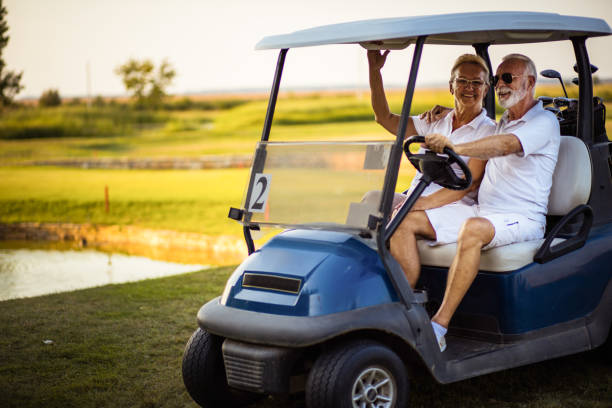 pareja de golfistas senior en coche de golf. - retirement golfer happiness relaxation fotografías e imágenes de stock