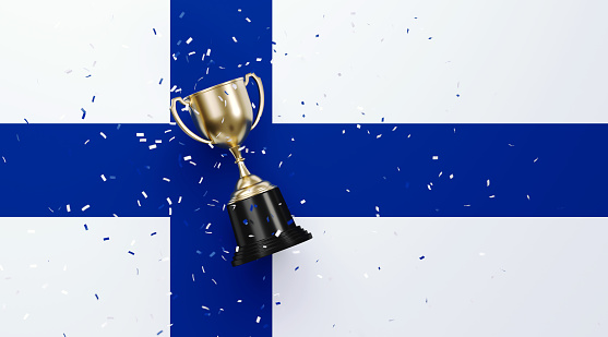 Colorful confetti falling onto a gold cup sitting over Finnish flag background. Horizontal composition with copy space. Front view. Championship concept.