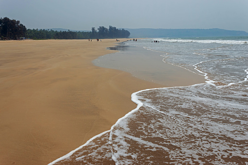 Guhagar beach view with small waves and large expanse of sand.  Ratnagiri Konkan, Maharashtra, India.