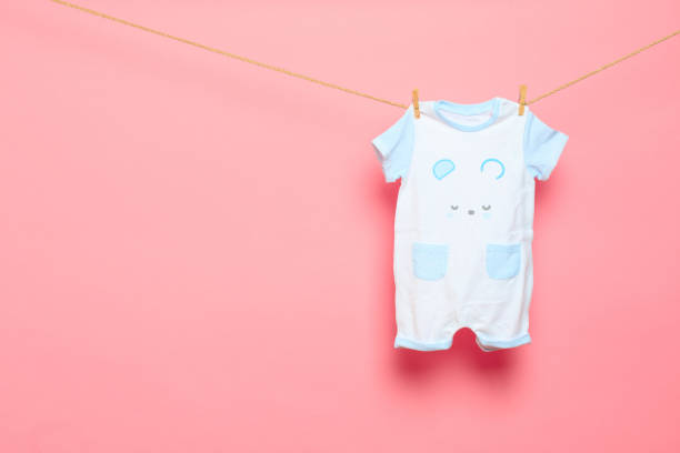 istock Baby clothes on a clothesline on pink background - Image 1313428447