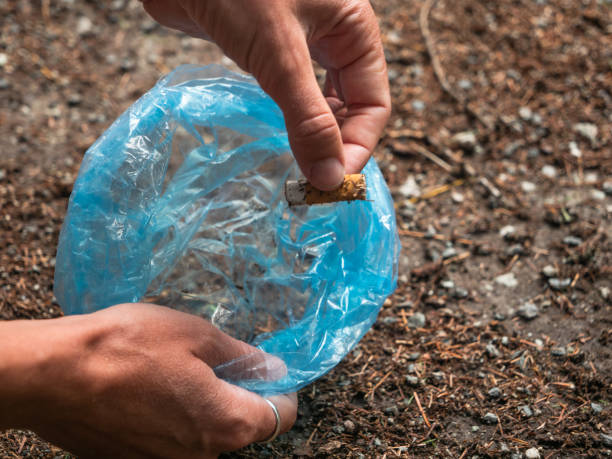 istock Close up of hand picking up cigarette butt in nature 1313428465