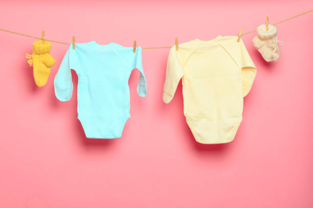 istock Baby clothes on a clothesline on pink background - Image 1313428502