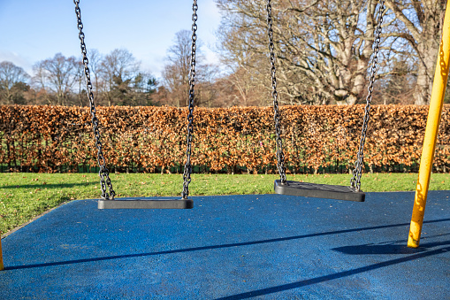 A shot of two empty swings on a sunny winters day.