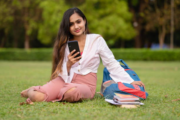 istock Young female student using mobile phone at park in campus 1313430577