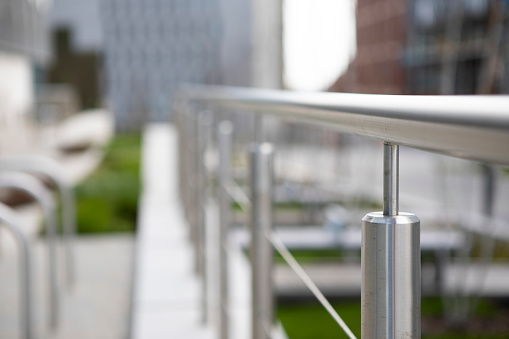 railing of a luxury house consisting of glass panels fastened with gray metal stainless steel paneling. the milky frosted glass barrier gives an airy impression. polished metal cover, window, milky