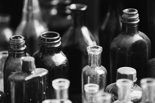 Many Old Deutsch Vintage Medical Glass Capacity. Detail Of Retro Chemical Pharmaceutical Science Researches. Small Bottles Different Sizes From Times Of World War II. WW2 WWII. Black And White.