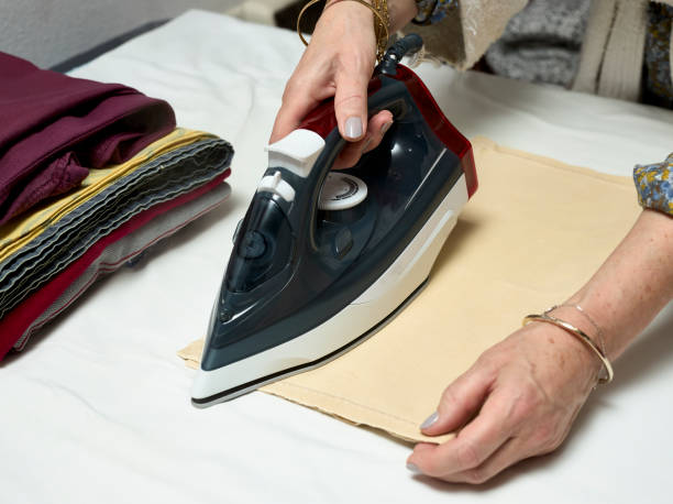 istock Woman's hands with an iron ironing clothes 1313435099