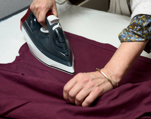 istock Woman's hands with an iron ironing clothes 1313435129