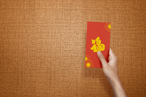 Hand holding red envelopes (Angpao) with a textured background. Happy Chinese New Year