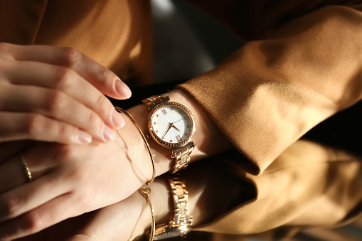 Woman wearing luxury wristwatch near mirror, closeup