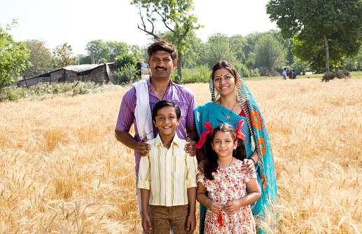 Happy parents with children standing in agricultural field