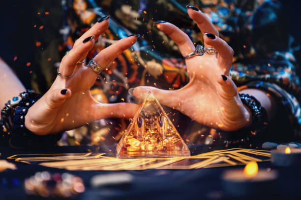 A witch conjures a magic glass pyramid. Hands close-up. Sparks flare up near the pyramid. The concept of witchcraft and divination A witch conjures a magic glass pyramid. Hands close-up. Sparks flare up near the pyramid. The concept of witchcraft and divination. runes photos stock pictures, royalty-free photos & images
