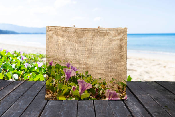 Design jute bag with flower pattern over blurred beach background, grocery bag, outdoor day light, ecological product, beach bag