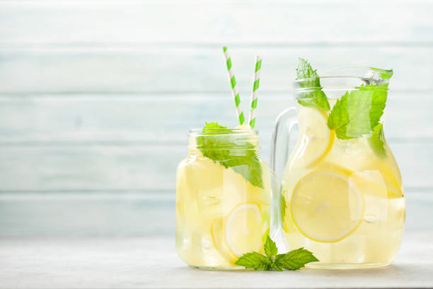 Lemon and mint homemade lemonade Mason jar and jug with lemon and mint homemade lemonade. With copy space mason jar lemonade stock pictures, royalty-free photos & images