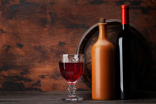 Wine bottles, glass of red wine and old wooden barrel. With copy space