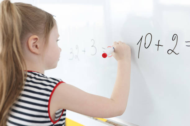 little girl writes math examples on white board - child thinking writing little girls imagens e fotografias de stock