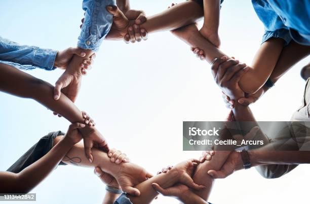 Low Angle Shot Of An Unrecognizable Group Of Businesspeople Standing Together And Holding Each Others Arms In A Circle Stock Photo - Download Image Now