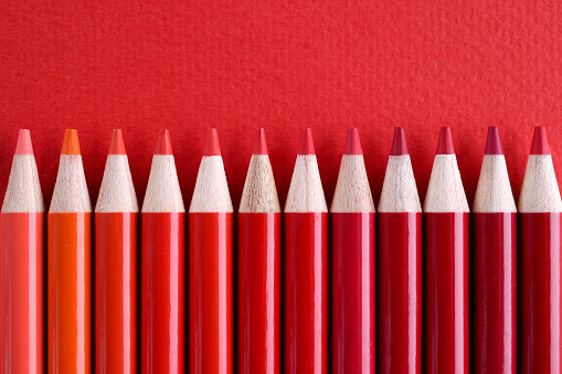 Closeup of many shades of red wooden pencils. Education or holidays concept