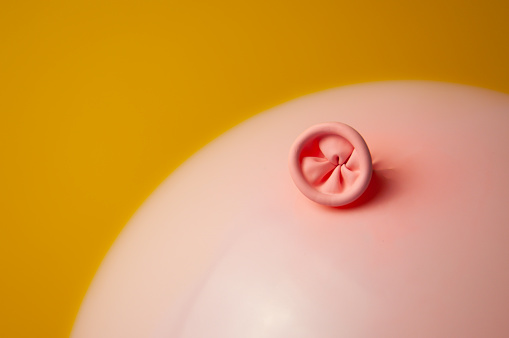 Una imagen de un globo rosa sobre un fondo amarillo. Metáfora ano, proctología, salud intestinal. photo