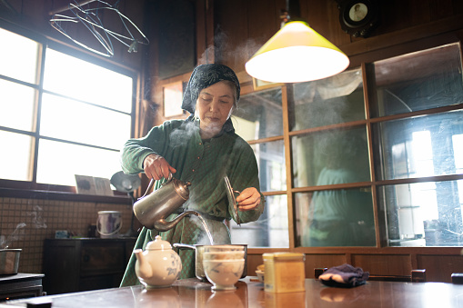 Senior Japanese woman making tea at home