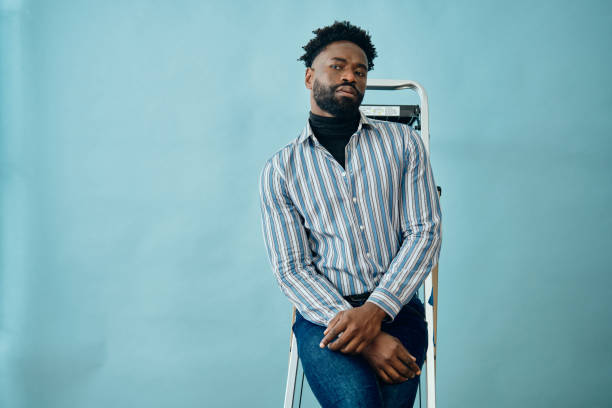 istock african american man standing on a ladder blue background 1313453885