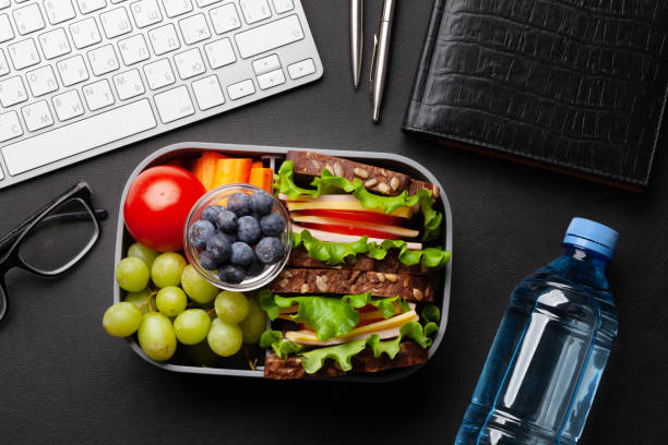 Healthy office lunch box with sandwich and fresh vegetables Healthy office lunch box with sandwich and fresh vegetables, water bottle, nuts and fruits on desk. Top view flat lay bottled water on table stock pictures, royalty-free photos & images