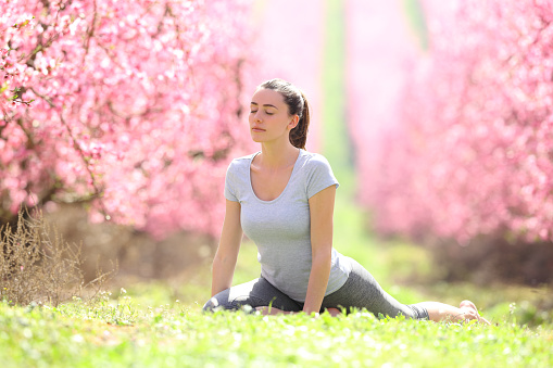 Woman practicing yoga exercise in a field in springtime