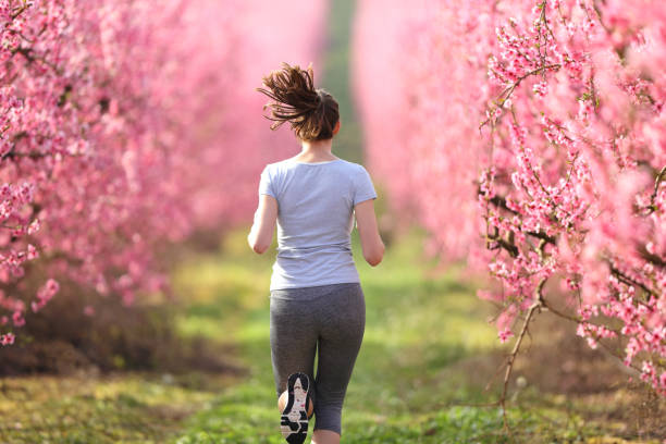 istock Back view of a runner woman running through a field in spring 1313455823