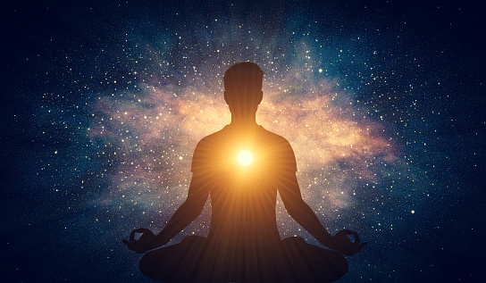 Man and soul. Yoga lotus pose meditation on nebula galaxy background. Zen, spiritual well-being