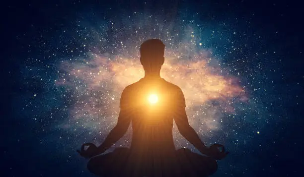 Photo of Man and soul. Yoga lotus pose meditation on nebula galaxy background
