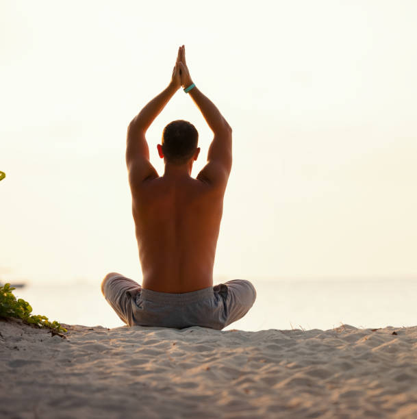 istock Calm man meditating on beach at sunset 1313457190