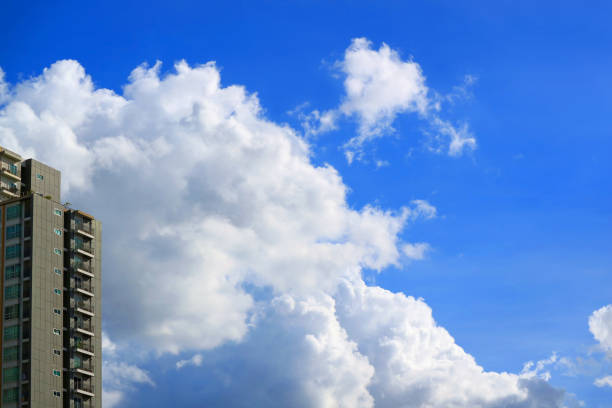 istock Pure white cumulus clouds on vibrant blue sky over a skyscraper 1313461370
