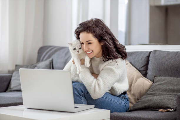 istock Dark-haired woman working on a laptop and hugging her cat 1313461427