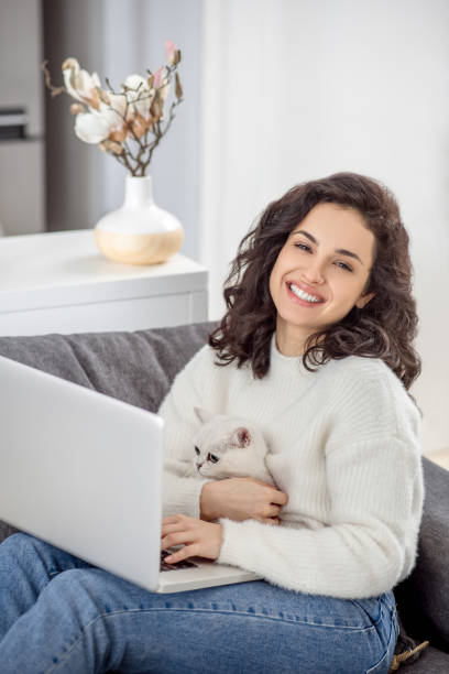 istock Dark-haired woman working on a laptop and hugging her cat 1313461438