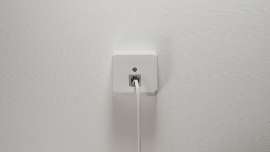 Internet Cord Into Wall Socket on a white wall