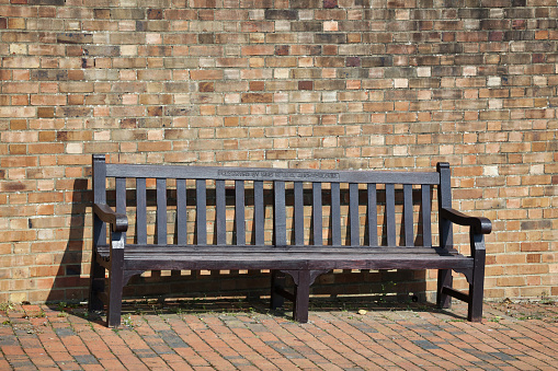 Eastbourne, England - April 20, 2021: A wooden memorial seat at Eastbourne, The seat has a memorial plaque in it.