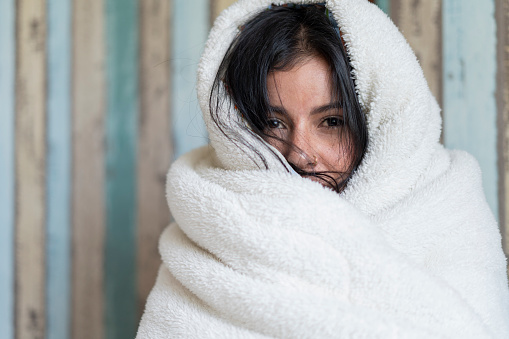 Young Latin woman from Bogota Colombia between 20 and 29 years old, wrapped in her blanket due to the high fever she has during the time she is in bed due to isolation