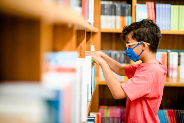 istock Boy in a face mask browsing books on shelves in a bookstore 1313467622