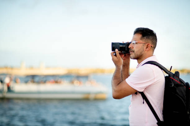 istock Man taking photos from a walkway of a scenic river view 1313467652