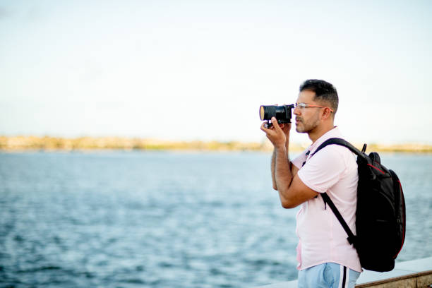 istock Man taking photos by a river while exploring the city 1313467654