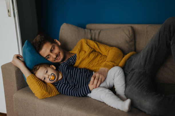 istock Young father and baby son relaxing on sofa 1313467804