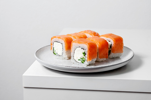 Philadelphia rolls with salmon fish, cucumber and cheese on plate on white background. Minimal concept.