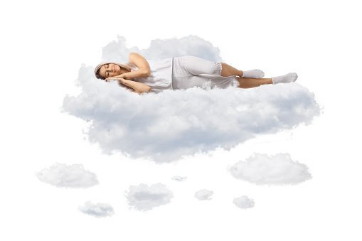 Young woman in pajamas sleeping on clouds isolated on white background