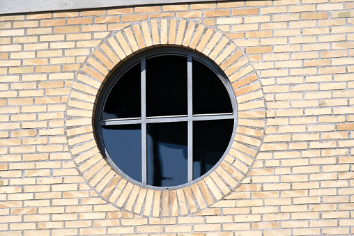 Round Window surrounded by brick wall facade. Photo taken April 20th, 2021, Zurich, Switzerland.