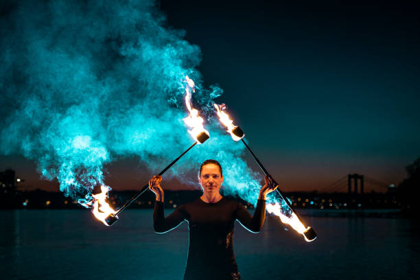 istock Fire artist posing with flaming torches creating blue smoke 1313473508