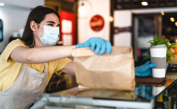 istock Bar owner working only with take away orders during corona virus outbreak - Young woman worker wearing face surgical mask giving takeout meal to customers - Healthcare and Food drink concept 1313474438