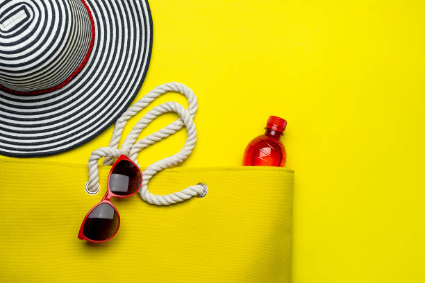 istock Yellow Beach Bag, striped hat and other beach stuff on yellow background 1313475726