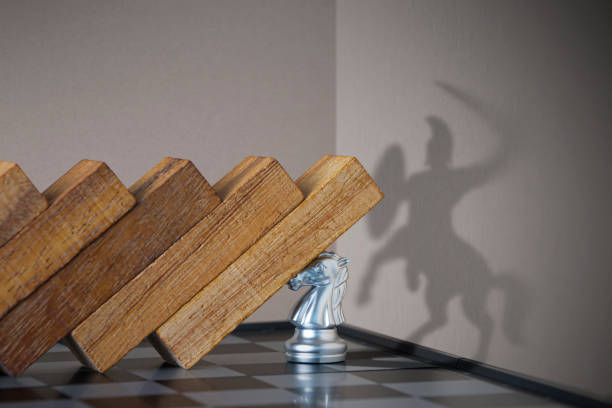 Crisis management, leadership, crisis solving or problem solving concept. Pawn chess stopping wooden dominoes from collapsing with centaur shadow on the wall. stock photo