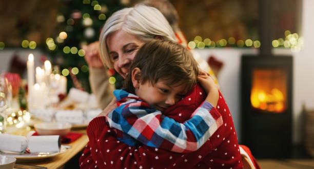 tiro de uma mulher idosa carinhosa abraçando seu neto durante uma festa de jantar de natal em casa - 5 month old - fotografias e filmes do acervo